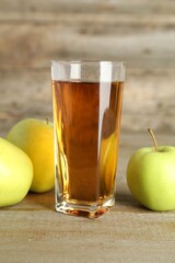 Glass of juice and apples on wooden table