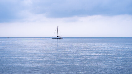 Sailing yacht race at sun light aerial. Yachting on serene seascape at open sea. Boat with big white spinnaker sail at ocean bay. Lonely ship cruise at water on summer sunny day.