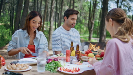 Cheerful friends gathering picnic in forest nature preparing food bbq closeup.