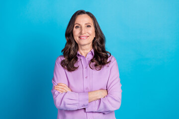 Photo of charming positive woman wear violet shirt hands crossed empty space isolated blue color...