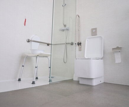 Hospital bathroom equipped with accessible fixtures for all types of users and an emergency pull cord. Includes a toilet, shower area with grab bars, a bath bench, and personal hygiene items