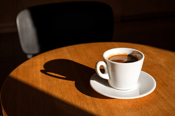 A cup of black coffee on the table in the sunlight