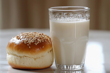 Warm bun with sesame seeds paired with a glass of milk