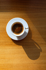 A cup of black coffee on the table in the sunlight