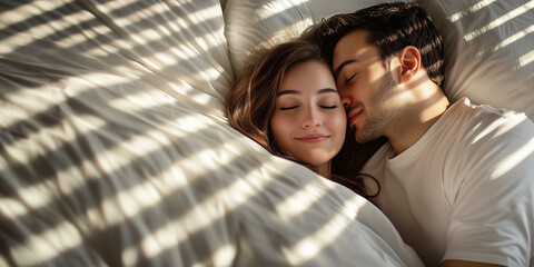 Young loving couple cuddling in bed in the morning. Young man and woman hugging laying on white sheets. Husband and wife in love.