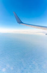 View from the airplane window at a beautiful cloudy sky and the airplane wing