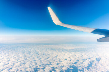 View from the airplane window at a beautiful cloudy sky and the airplane wing