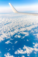 View from the airplane window at a beautiful cloudy sky and the airplane wing