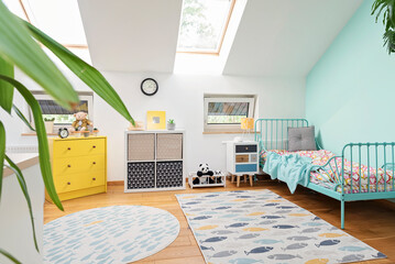 Children room in the attic with turquoise bed, modern carpet on wooden floor and colourful decoration at cozy home. Interior of room child.