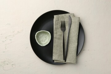 Stylish plate, cutlery, napkin and sauce bowl on beige textured table, top view