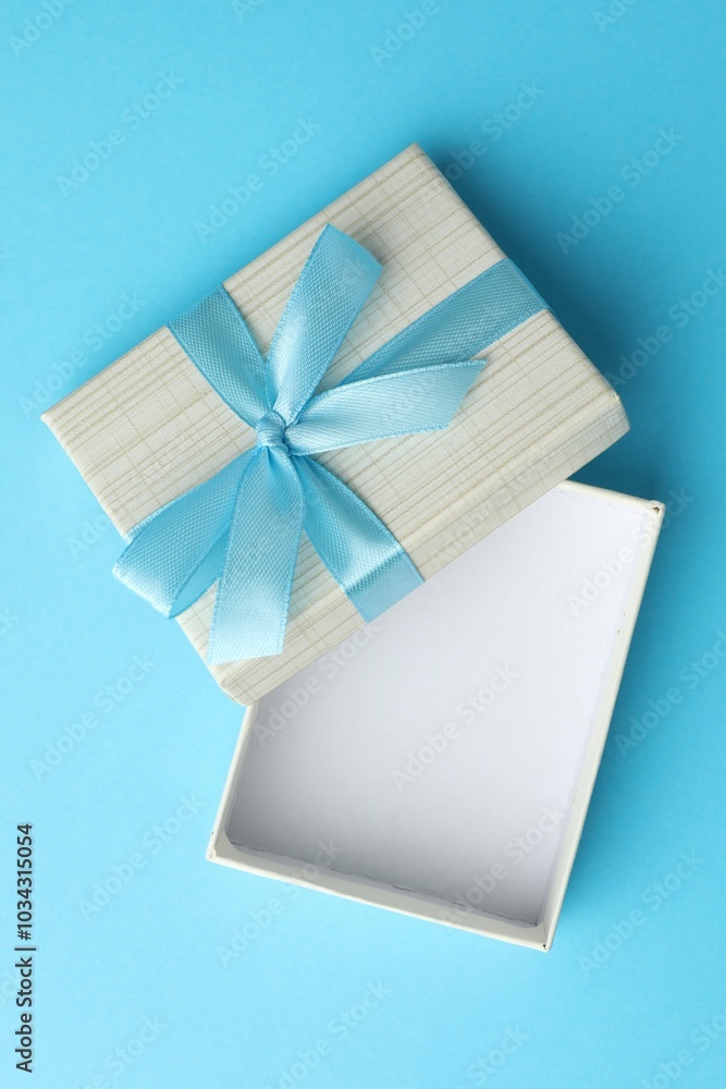 Wall mural Gift box with bow on light blue background, top view