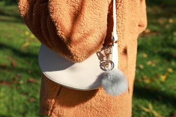 Woman with faux fur keychain on her bag outdoors, closeup