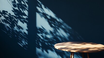 Empty table casting organic shadows on a dark blue wall, offering a stylish background -
