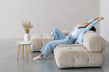 Calm satisfied woman stretching on couch thinking of pleasant lazy day, dreaming and planning...