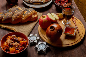 Hala, honey, apple and grenades and wine of the Chelnt and fish on the table with menora and burning candles in honor of Rosh Hashan