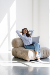 Fototapeta premium Young woman relaxing with her hands behind her head and sitting on a chair