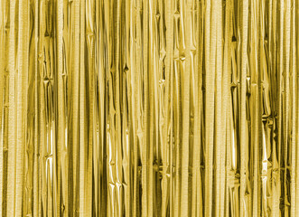 Yellow golden foil strip blurred abstract background. Curtain hanging on wall. Festive, Christmas, New Year or anniversary party concept. Decorative wallpaper