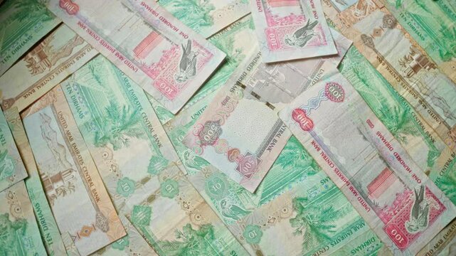 United arab emirates dirham banknotes in various denominations spread out in an overlapping pattern.