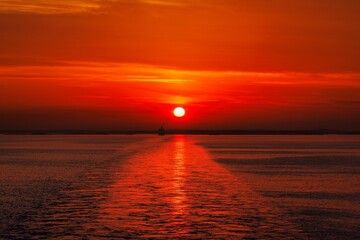 Stunning sunset over a calm ocean with a ship on the horizon