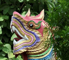 Close-up of a colorful, traditional dragon sculpture with lush green foliage in the background