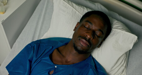 Fototapeta premium Asleep in the hospital bed, an overhead view captures the African patient in a calm moment of rest from above.