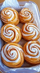 Fototapeta premium Warm cinnamon rolls sit invitingly in a dish, drizzled with creamy icing, creating a delicious breakfast treat perfect for sharing with friends and family