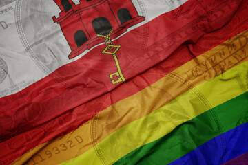 waving colorful flag of gibraltar and gay rainbow flag on the dollar money background. finance...