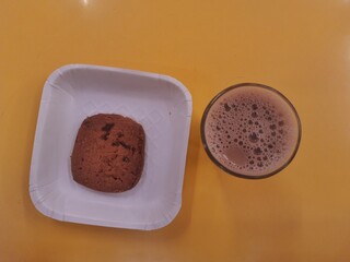 A cup of tea with cookie with Yellow background.