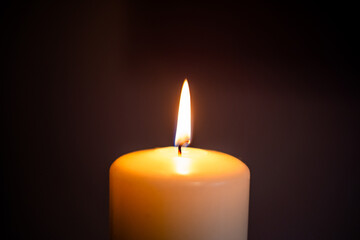 A single candle flame illuminating darkness in a serene indoor setting during evening hours....