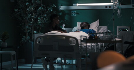 Devoted partner sits beside her boyfriend in the hospital, offering solace and support during his recovery.