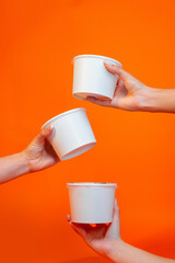 Hands holding white packaging recipients on colored background