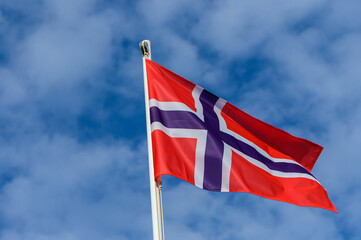 Norwegian flag waving proudly against a backdrop of clear blue skies on a bright sunny day in Norway