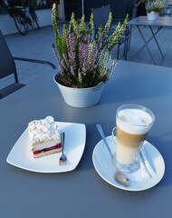 Kawa latte i ciasto na stoliku w restauracji na zewnątrz.
