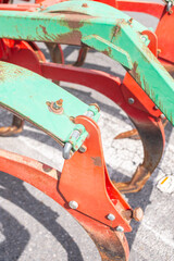 used and rusty plow painted red and green, mechanical agricultural equipment concept