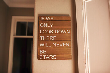 Interior decoration, motivational quote and poster on wall in home for encouragement or inspiration. Art, ideal and wooden sign hanging at window in apartment for background, growth or wallpaper