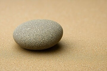 A Single Gray Pebble Resting on a Bed of Fine Sand