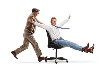 Elderly man pushing a businessman seated in an office chair