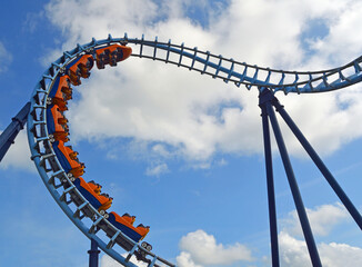 Roller coaster  ride filled  with thrill seekers against blue sky 
