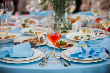 Exquisite table setting with empty plates and polished cutlery, accented by the dreamy atmosphere of a wedding ceremony nearby