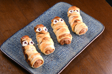 Sausage mummies wrapped in puff pastry decorated for Halloween fun dish