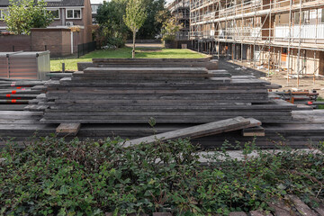 wooden planks used in scaffolding are stacked outside