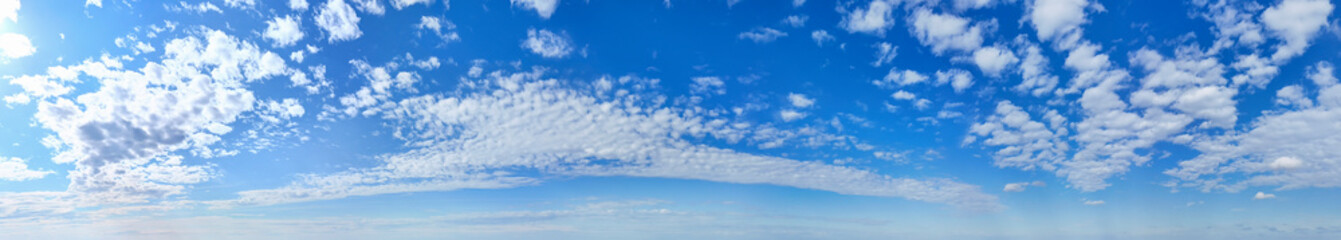 A panoramic view of a clear blue sky with scattered clouds. Perfect for backgrounds or projects related to nature and tranquility.