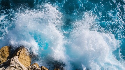 Obraz premium Waves crash against rocky shore, blue ocean water.