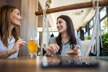 Two girl best friends having out at the restaurant. Drinking coffee and orange juice. They gossip, laugh and have fun time.