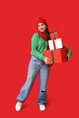 Beautiful young woman with Christmas gifts on red background