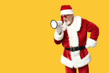 Santa Claus in sunglasses with megaphone screaming on yellow background