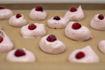 Delicious meringue cookies topped with fresh cherries cooling on a baking sheet in a cozy kitchen