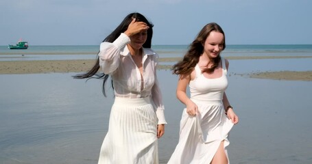 two girls friends walking on the beach LGBT white dress run dancing beautiful young women asian european female against the background of the sea river shallow water