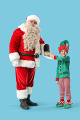Santa Claus and cute little elf putting letters in mail box on blue background