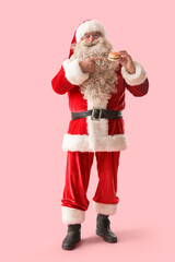 Santa Claus pointing at tasty burger on pink background
